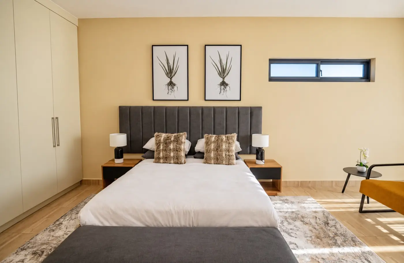 Main bedroom with a grey headboard and armchair